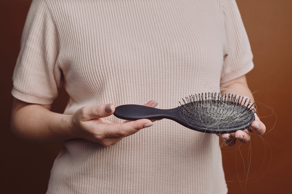 Frau hält eine Bürste voller Haare in der Hand